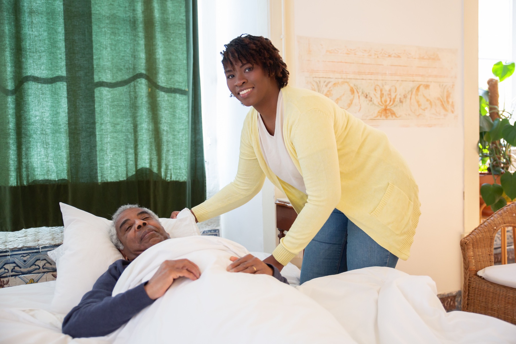 A caregiver offering bedside support to an older adult at home